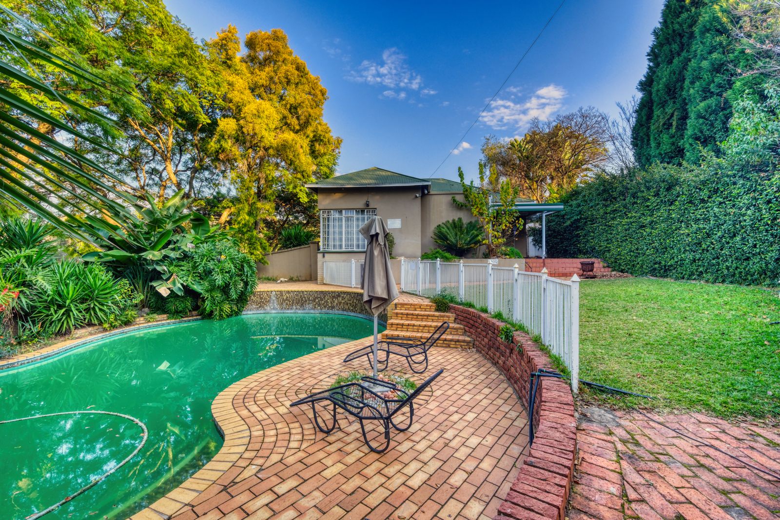 Landscaped backyard with patio, pool and lush planting
